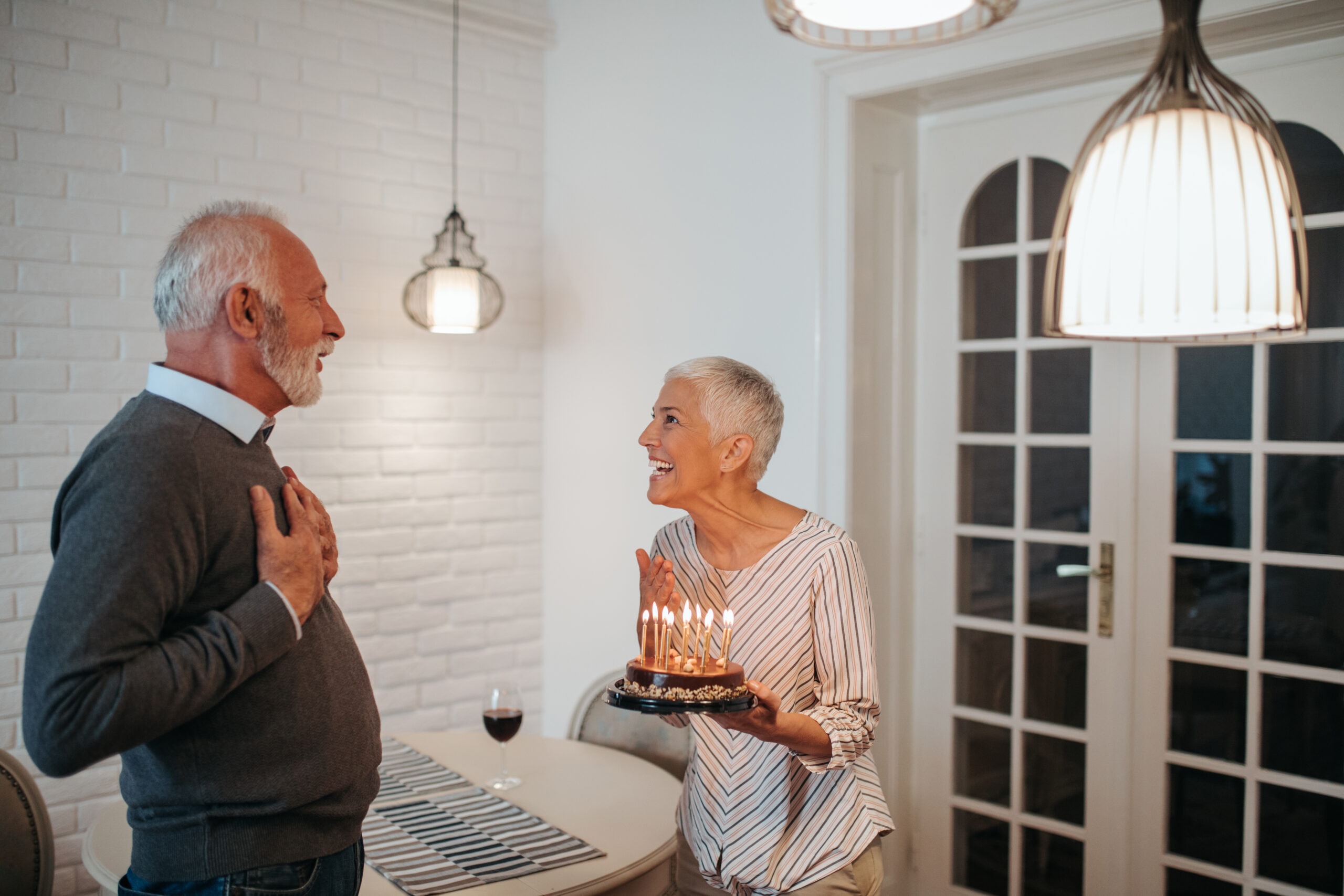 Mature woman surprising her husband with a birthday cake